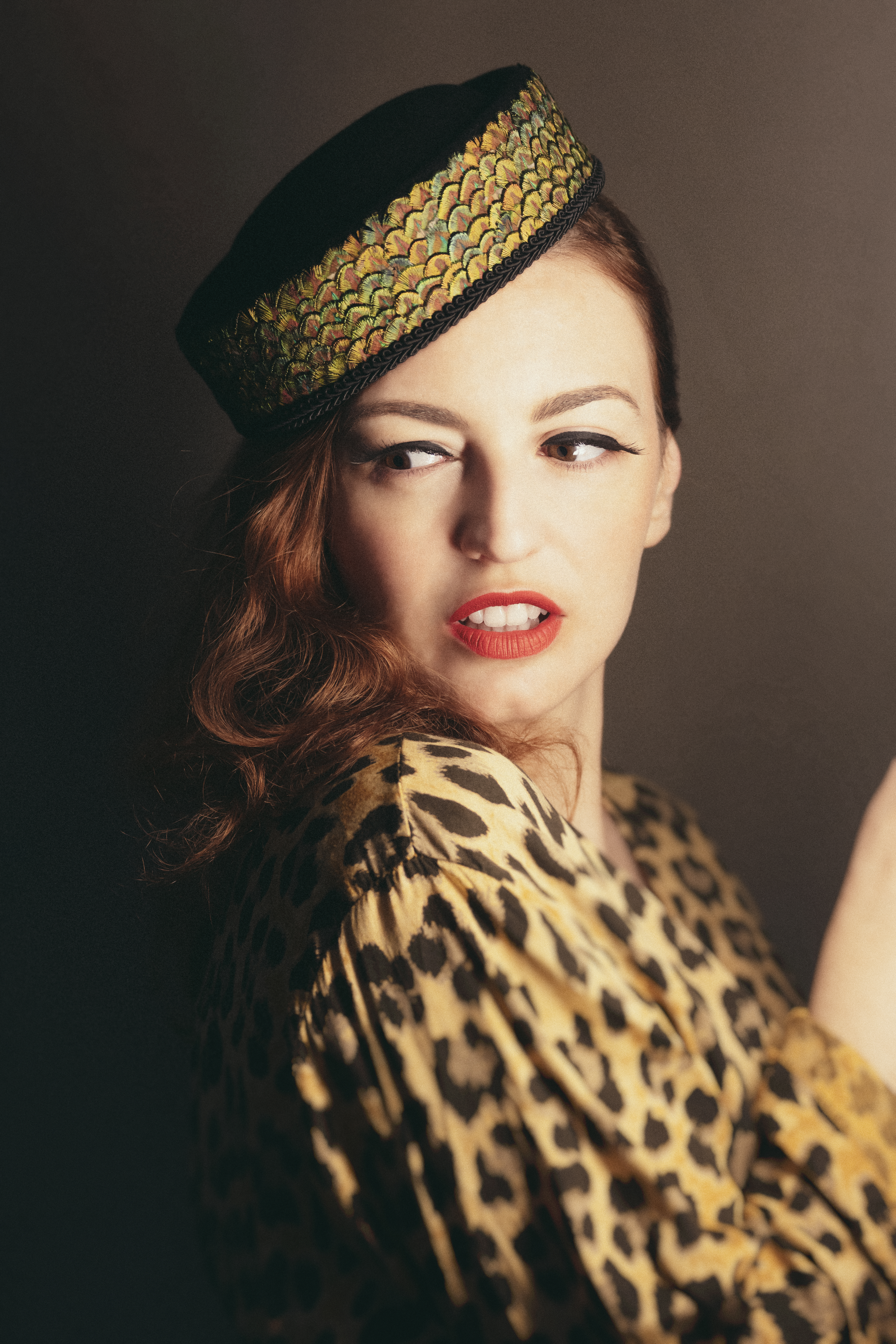 Bridget 27, en robe léopard et coiffe à motifs, pose de profil dans une ambiance chaleureuse, photographiée par Eve Saint Ramon.