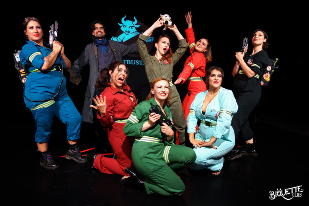 La troupe du Biquette Club pose sur scène en tenues colorées inspirées des Ghostbusters, armées de faux équipements, dans une ambiance joyeuse et théâtrale.