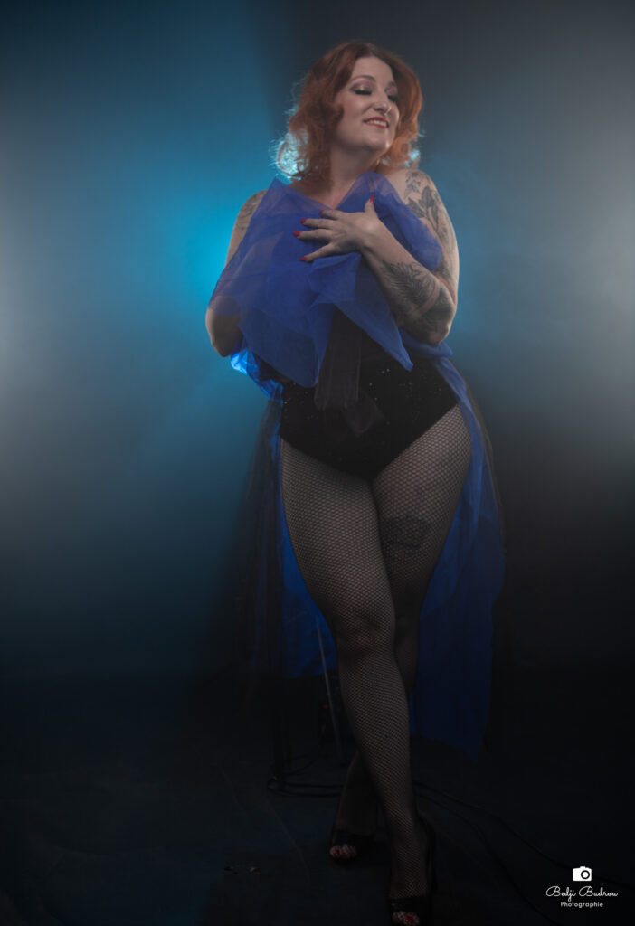Dotty Mac Lane sur scène, enveloppée d’un voile bleu, photographiée par B comme Boudoir dans une ambiance dramatique.