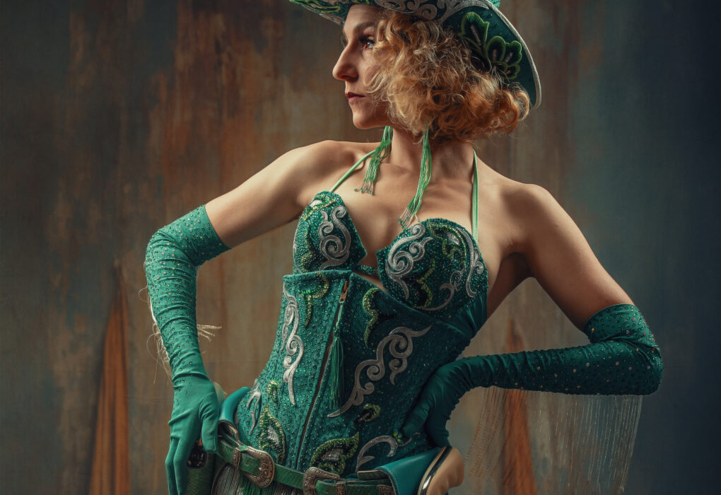 Artiste burlesque Coco Charnelle en cow-girl glamour, corset vert orné de motifs, chapeau assorti et gants longs, photographiée par Olivier Charlet