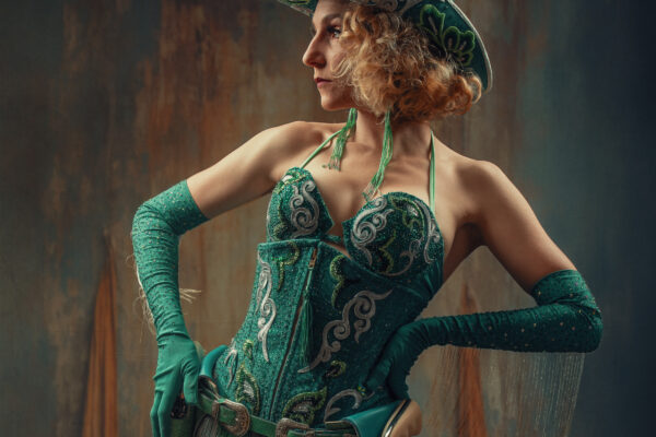 Artiste burlesque Coco Charnelle en cow-girl glamour, corset vert orné de motifs, chapeau assorti et gants longs, photographiée par Olivier Charlet