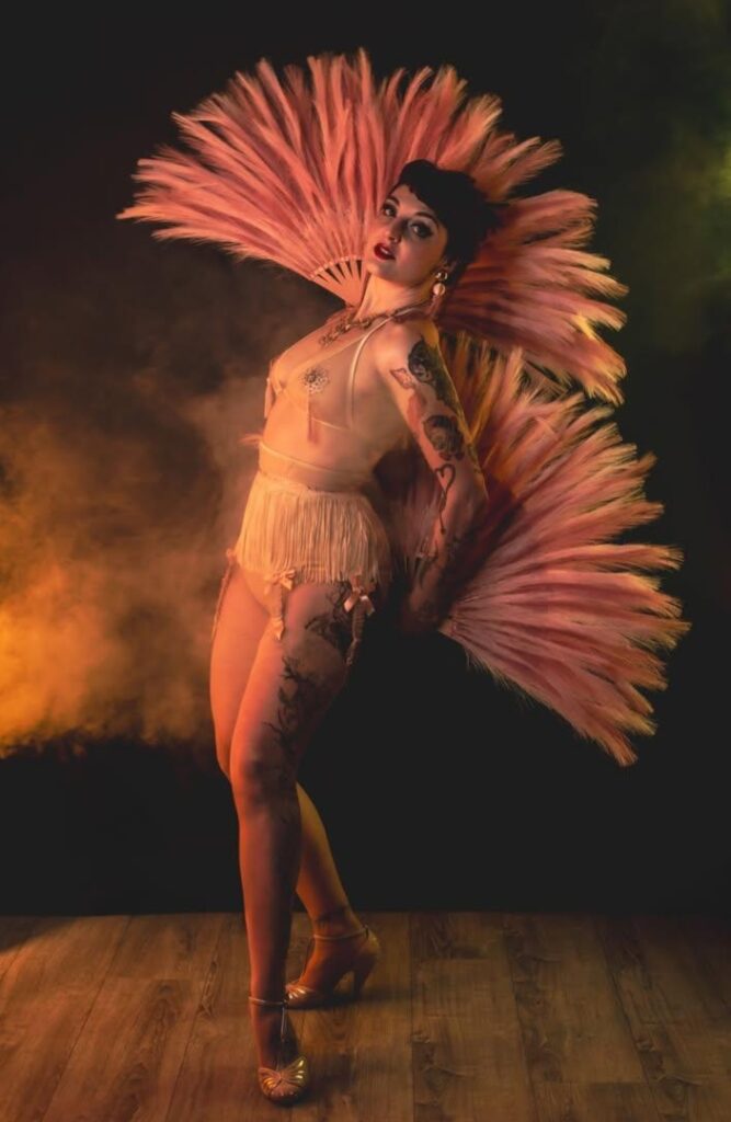 Madâme Plum'ti en costume burlesque nude avec grandes plumes roses sur scène
