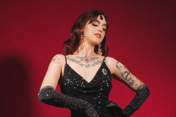 Lady Luciole en robe longue noire pailletée, gants longs et talons, posant sur fond rouge, silhouette glamour burlesque – Photo Veronica Marxx