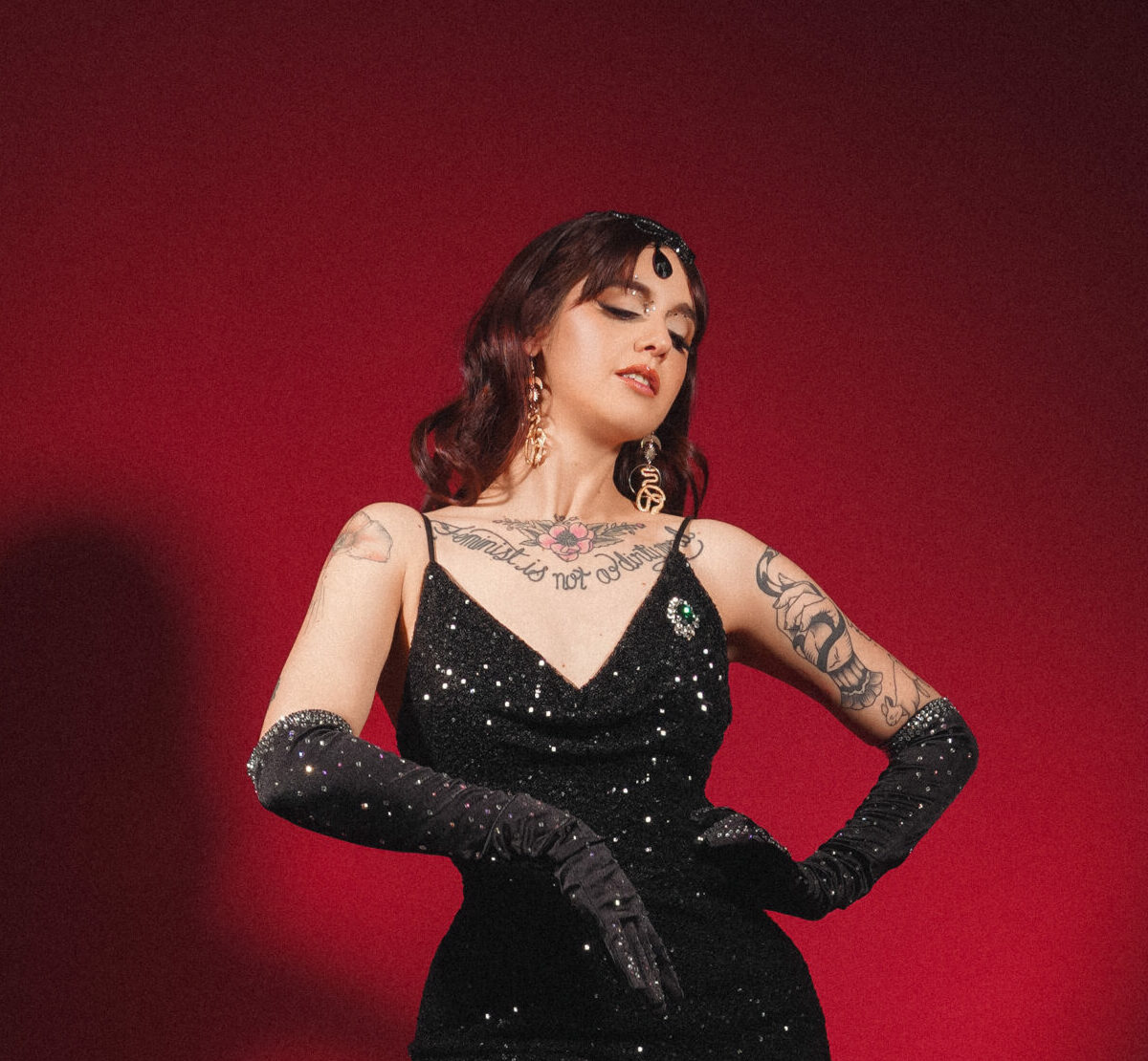 Lady Luciole en robe longue noire pailletée, gants longs et talons, posant sur fond rouge, silhouette glamour burlesque – Photo Veronica Marxx