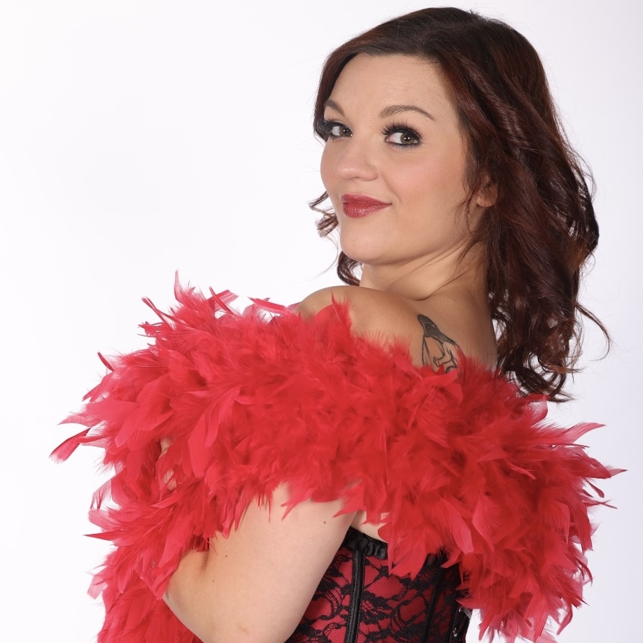 Portrait de l’artiste burlesque Stella Luna de trois quarts, portant un corset noir et rouge et un boa de plumes rouges, photographiée par kumasmile88_photo_courchevel.