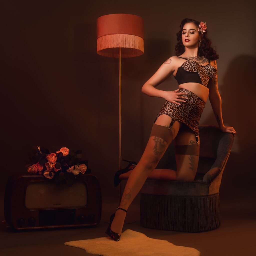 Lady Luciole en lingerie burlesque léopard, bas nylon et escarpins, posant près d’un fauteuil vintage, d’une radio et d’un lampadaire rétro – Photo Julien Cuinet