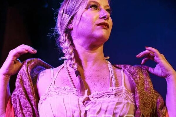 Artiste burlesque Milly Résille sur scène en bustier clair et châle brodé sous un éclairage violet, photographiée par Eric Delage.