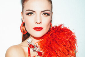 Danseuse burlesque Tara D’Arson en tenue de scène rouge avec boa à plumes, photographiée par Kahneda Photography.
