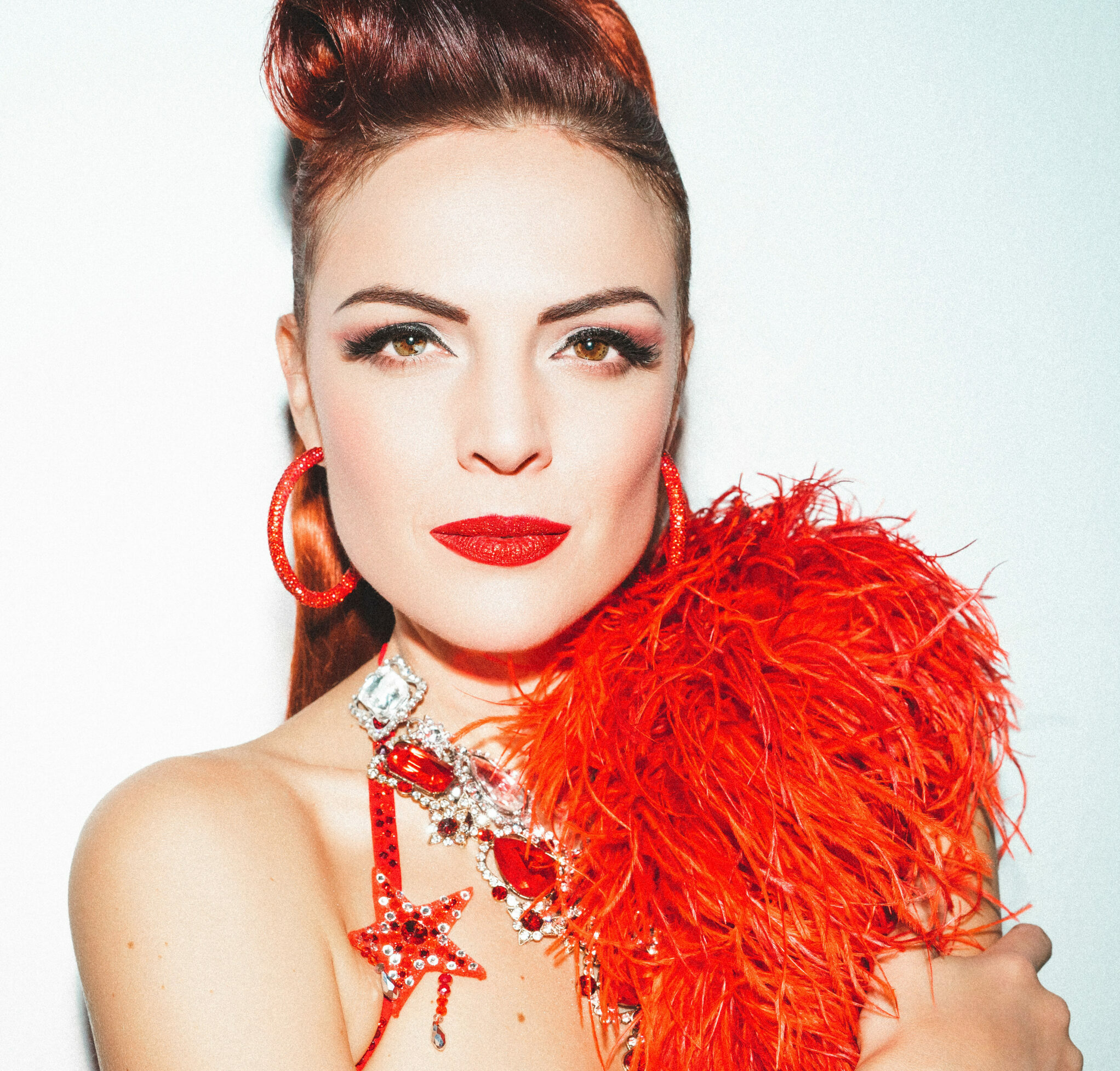 Danseuse burlesque Tara D’Arson en tenue de scène rouge avec boa à plumes, photographiée par Kahneda Photography.