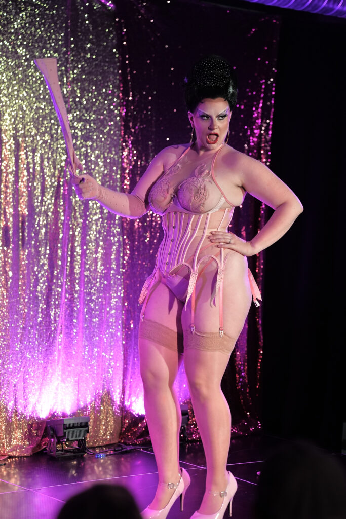 Médée The Bwitch, performeuse burlesque, en pose scénique avec lingerie glamour et lumière de cabaret.