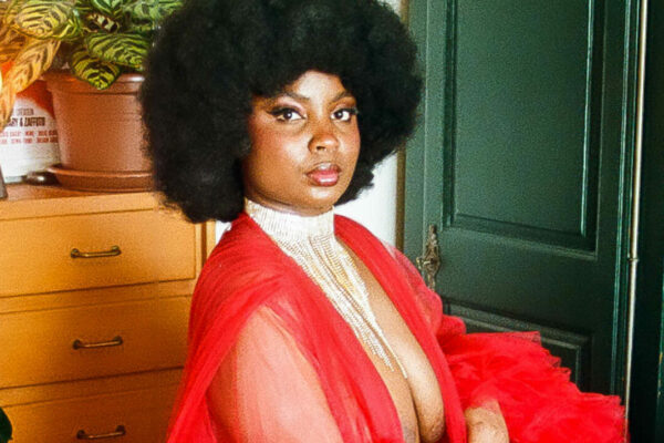 Nubsaphrodite, artiste burlesque, en kimono rouge transparent et chevelure afro, décor plantes et poster Fantasma.