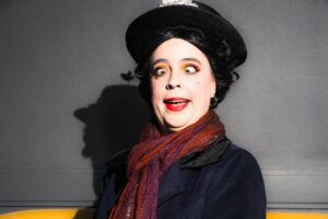 Marine Poppin's costumière effeuilleuse burlesque Rennes chapeau noir écharpe rouge maquillage théâtral canapé jaune