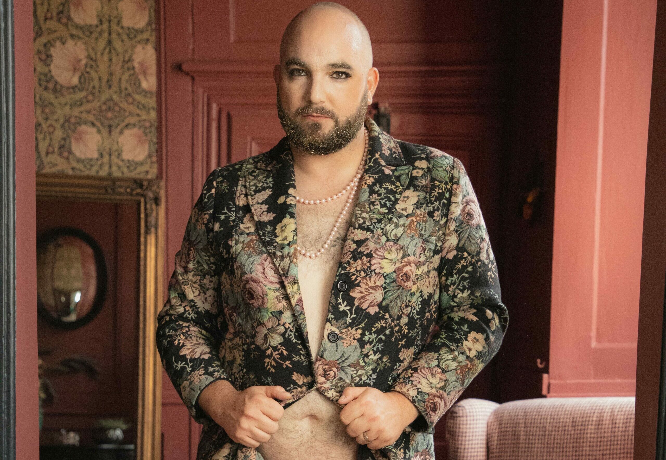 Portrait Monsieur Paul Piette, artiste burlesque, veste fleurie ouverte et slip doré, fond rouge.