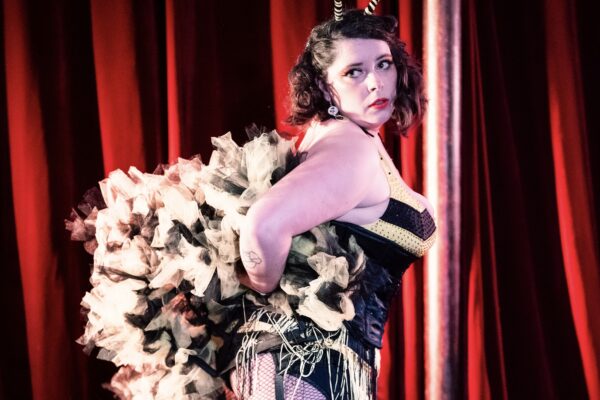 Lulu Toute Crue artiste burlesque ronde costume noir plumes blanches rayures jarretières sur scène cabaret