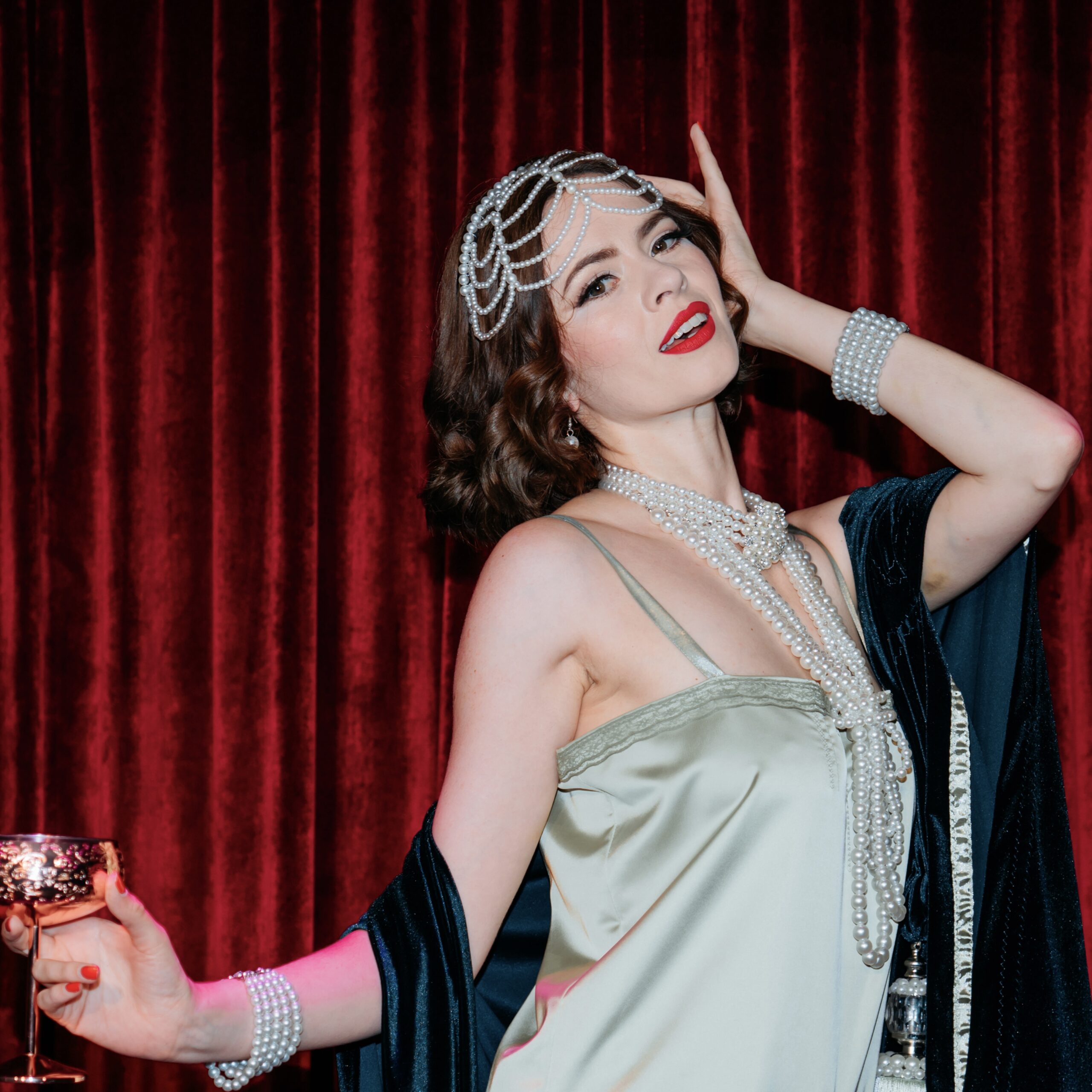 Portrait de l'artiste burlesque Kitty Whispers dans un style Gatsby avec une coiffe et des colliers en perles de nacre. Photo par Photographe Pro sur Mein Schiff Relax.